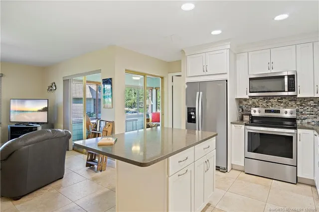 a kitchen with stainless steel appliances a stove a refrigerator a oven a sink with a dining table and chairs