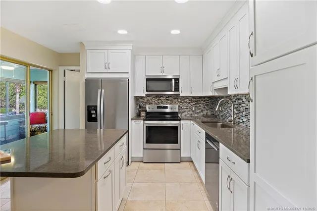 a kitchen with white cabinets and sink