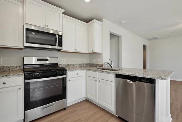 a kitchen with stainless steel appliances granite countertop a stove microwave and sink