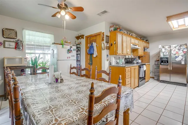 a kitchen with stainless steel appliances kitchen island granite countertop a refrigerator a stove a oven with white cabinets and wooden floor