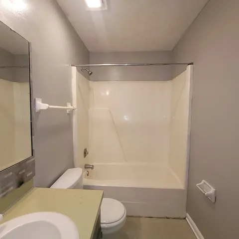 a bathroom with a granite countertop bathtub shower sink vanity and toilet