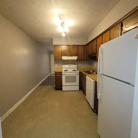 a kitchen with a refrigerator a stove top oven and cabinets