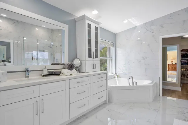 a spacious bathroom with a double vanity sink mirror and bathtub