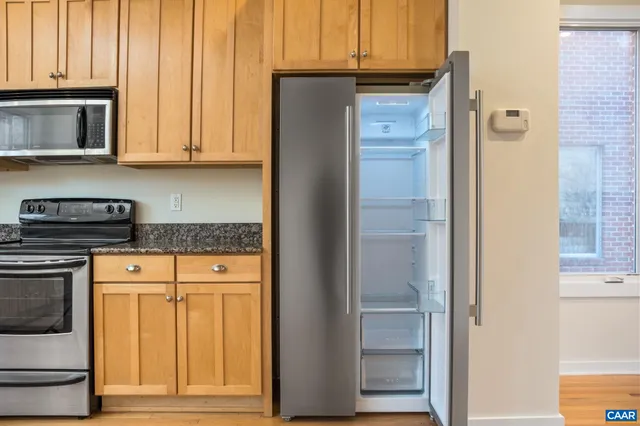 a kitchen with stainless steel appliances granite countertop cabinets and a refrigerator with wooden floor