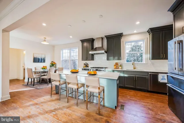 a large kitchen with lots of furniture a sink appliances and wooden floor