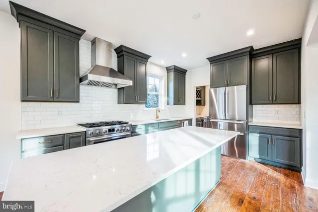 a kitchen with stainless steel appliances granite countertop a stove a refrigerator and a sink with wooden cabinets