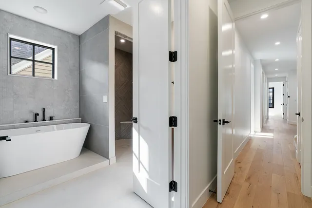 a bathroom with a white tub shower sink and mirror