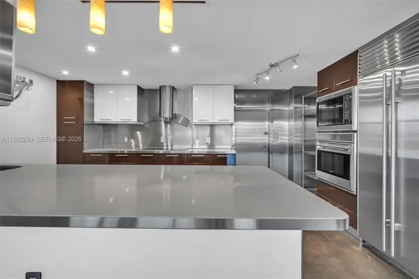 a large kitchen with kitchen island a large counter top stainless steel appliances and cabinets