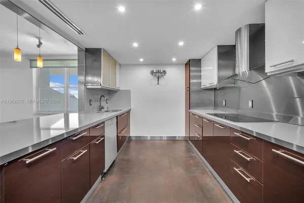 a large kitchen with stainless steel appliances a large counter top a stove and a sink