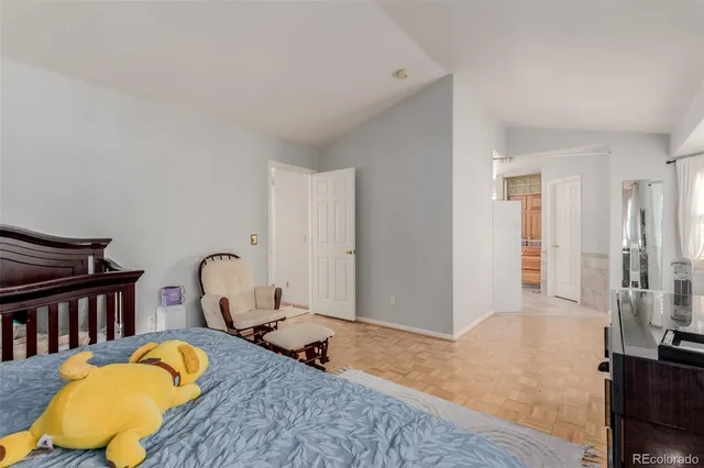 a bedroom with a bed and dresser with wooden floor