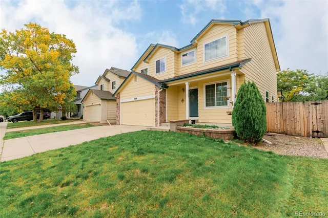 a view of a white house with a small yard and large tree