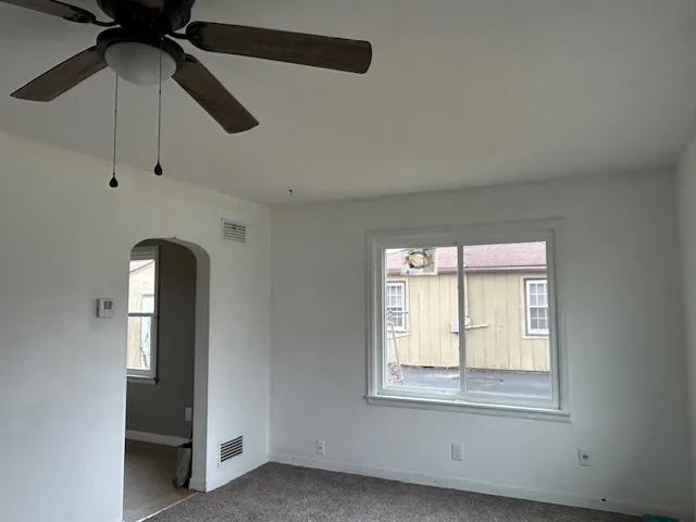 an empty room with a window and a ceiling fan