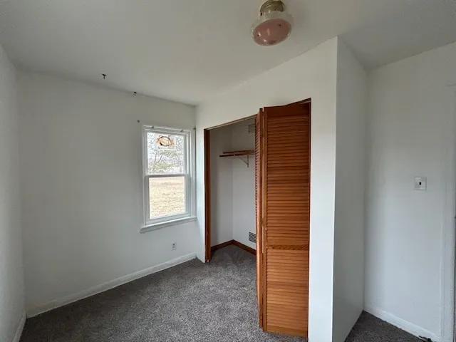 a view of an empty room with window and closet area