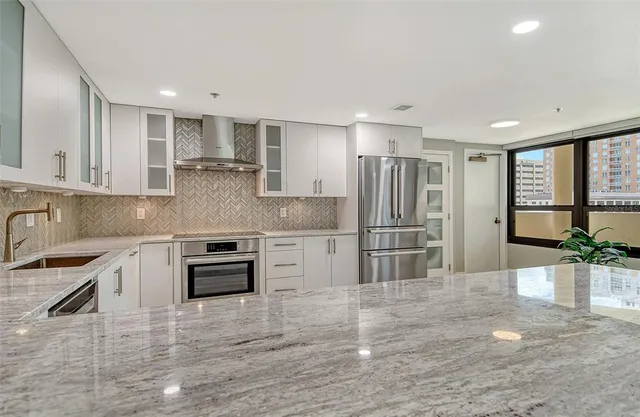 a kitchen with stainless steel appliances granite countertop a refrigerator sink and stove