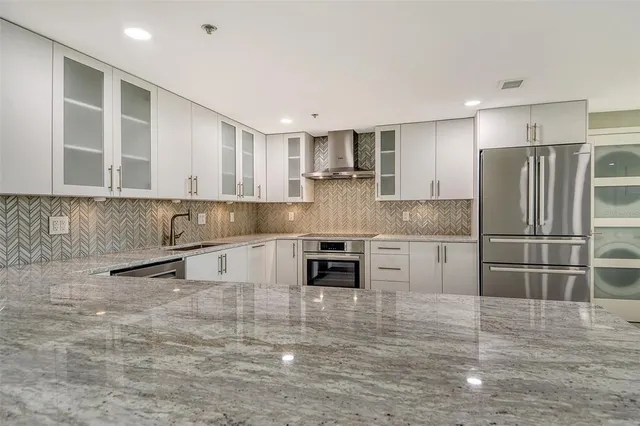 a kitchen with stainless steel appliances granite countertop a refrigerator and a stove top oven