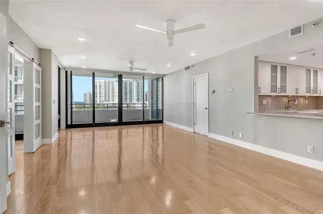 a view of an empty room with wooden floor and a window