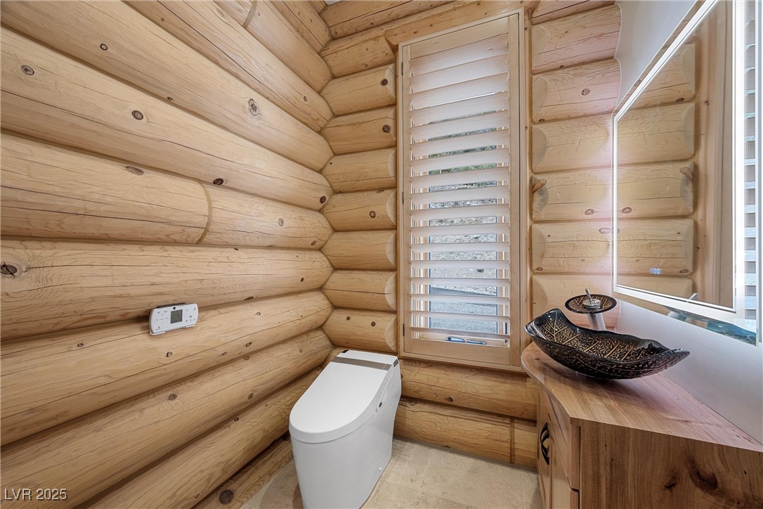 4927 Snow White Road Mount Charleston, NV 89124 - Photo 20 of 65 Main level powder room with log walls, vanity, and smart toilet with heated seat and bidet