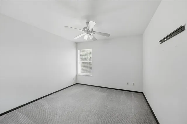 an empty room with a window and a ceiling fan