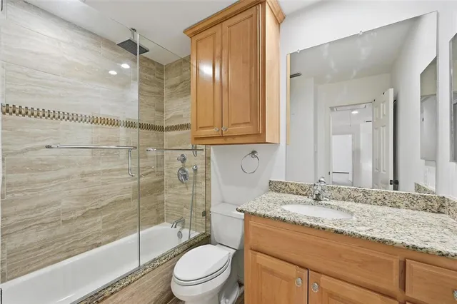 a bathroom with a granite countertop sink a toilet and shower