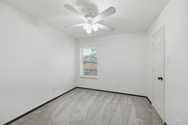 an empty room with window and ceiling fan