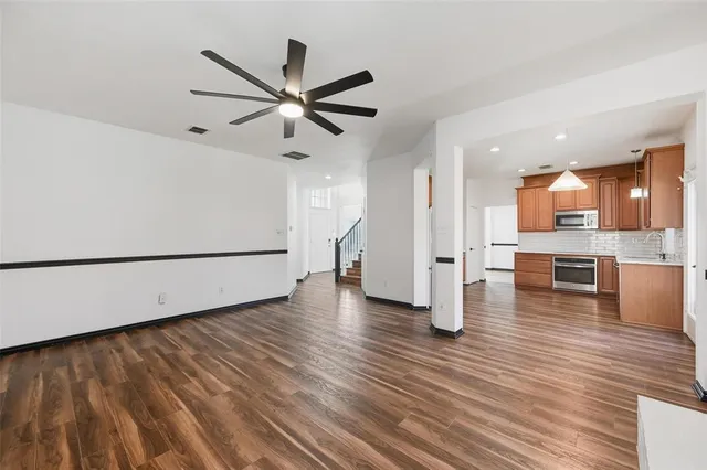 a view of a living room with wooden floor and a ceiling fan
