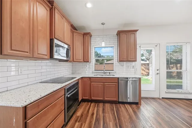 a kitchen with stainless steel appliances granite countertop wooden cabinets a sink and dishwasher with wooden floor