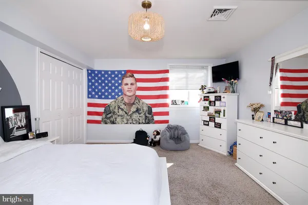 a bedroom with a bed and flat tv screen on dresser