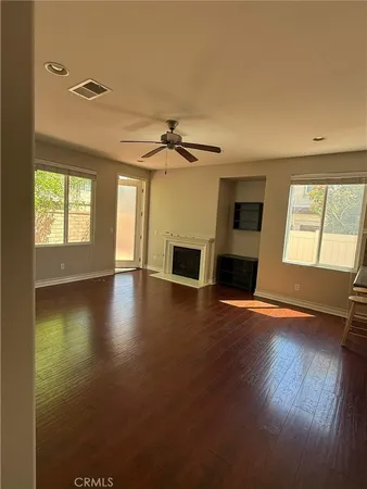 an empty room with wooden floor fireplace and windows