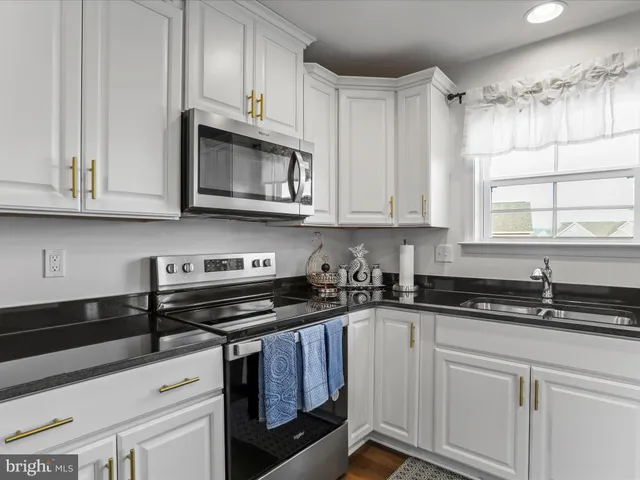 a kitchen with granite countertop white cabinets and black appliances
