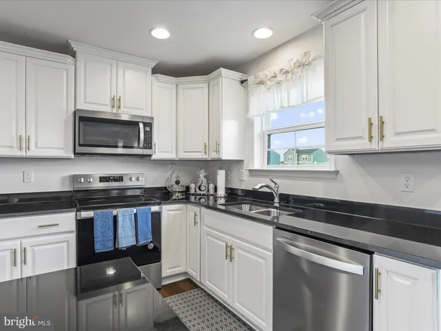 a kitchen with granite countertop a sink a stove and cabinets