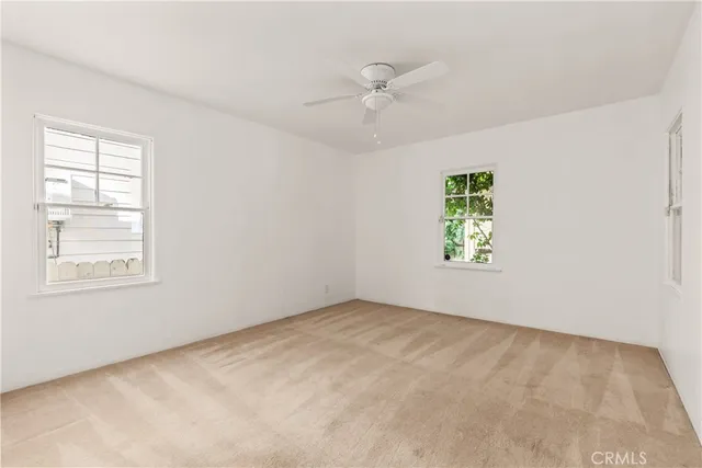 an empty room with windows and fan