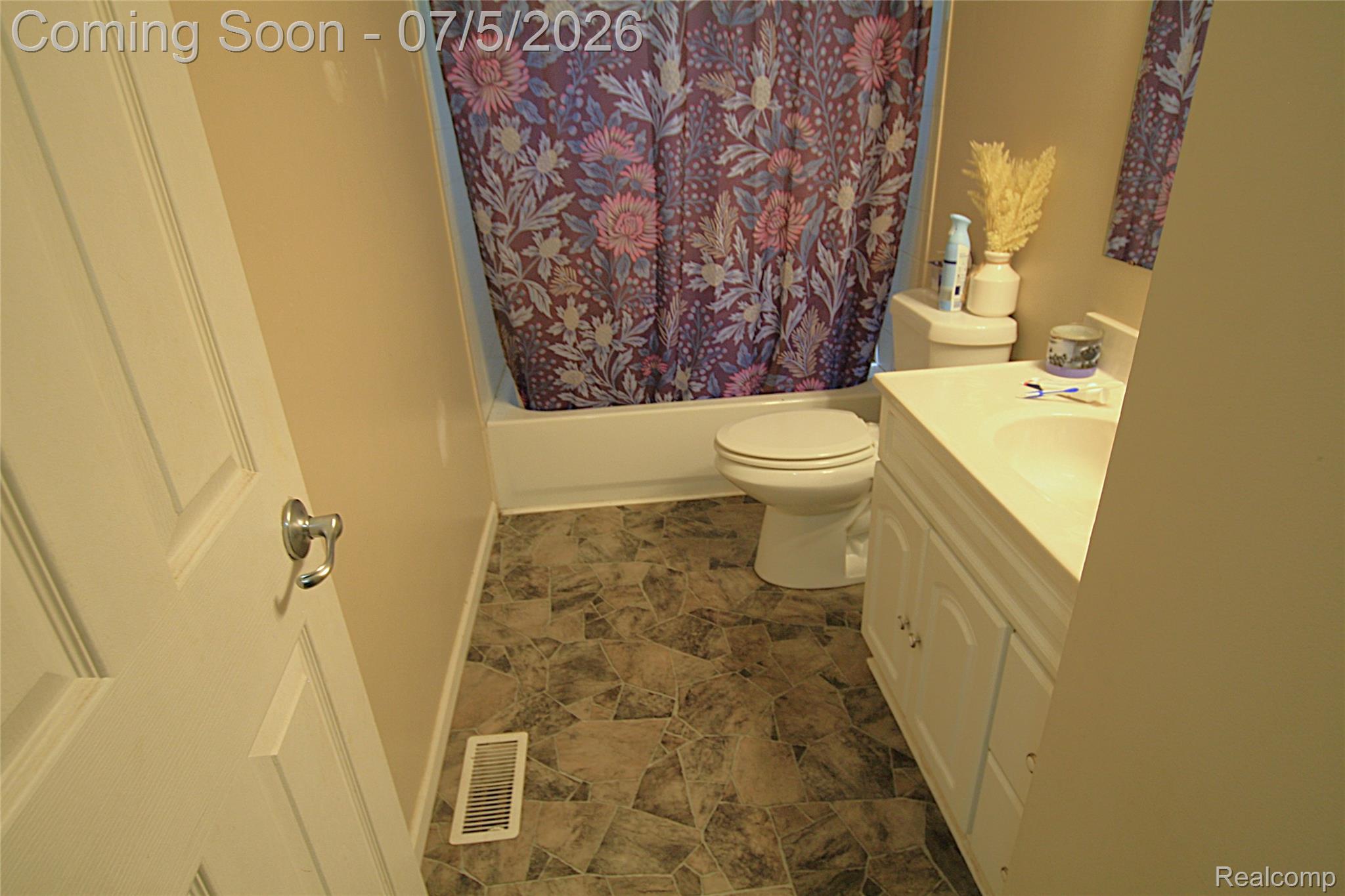 12403 Willard Road Montrose, MI 48457 - Photo 26 of 30 Bathroom featuring a white vanity with cabinet storage, an integrated sink, a standard toilet, and a white bathtub with shower
