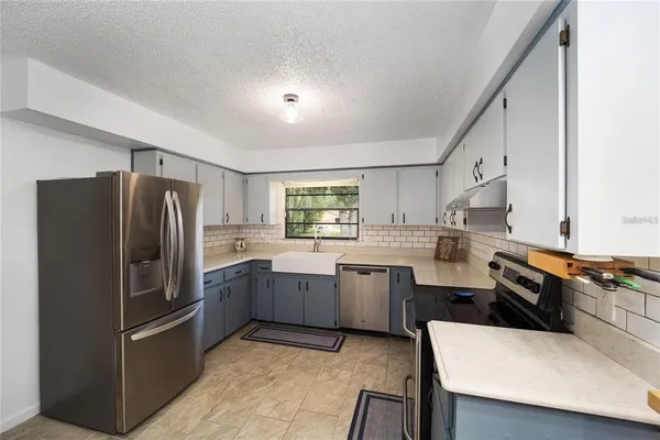 a kitchen with stainless steel appliances granite countertop a sink stove refrigerator and cabinets