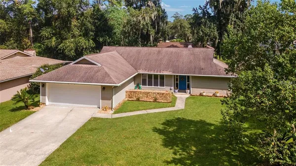 a aerial view of a house next to a yard with plants and large trees