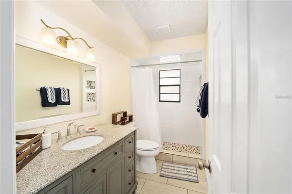 a bathroom with a granite countertop sink toilet a mirror and shower
