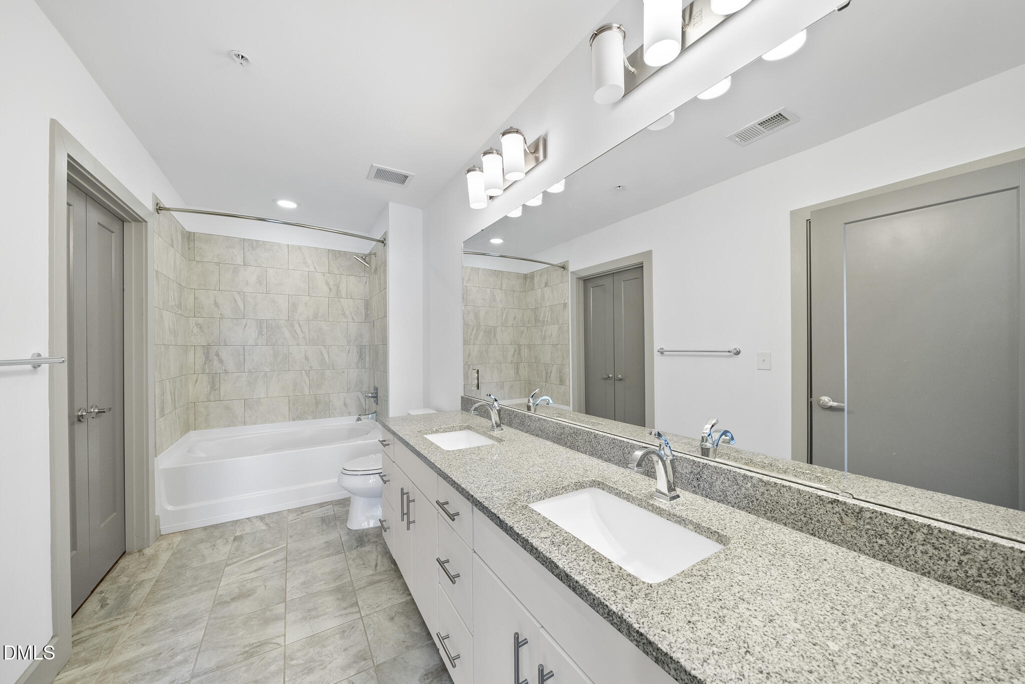 1300 St Marys Street, Unit 207 Raleigh, NC 27605 - Photo 15 of 18 a bathroom with a granite countertop double vanity sink a large mirror and a bathtub
