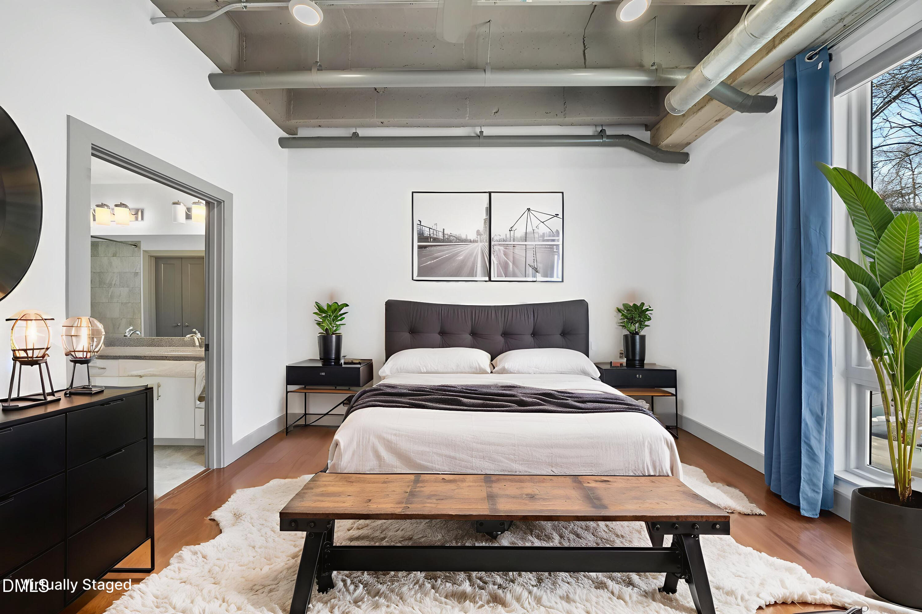 1300 St Marys Street, Unit 207 Raleigh, NC 27605 - Photo 4 of 18 a bedroom with a bed a mirror and a potted plant