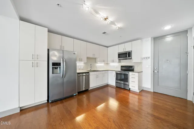 a large kitchen with stainless steel appliances a refrigerator and a stove top oven
