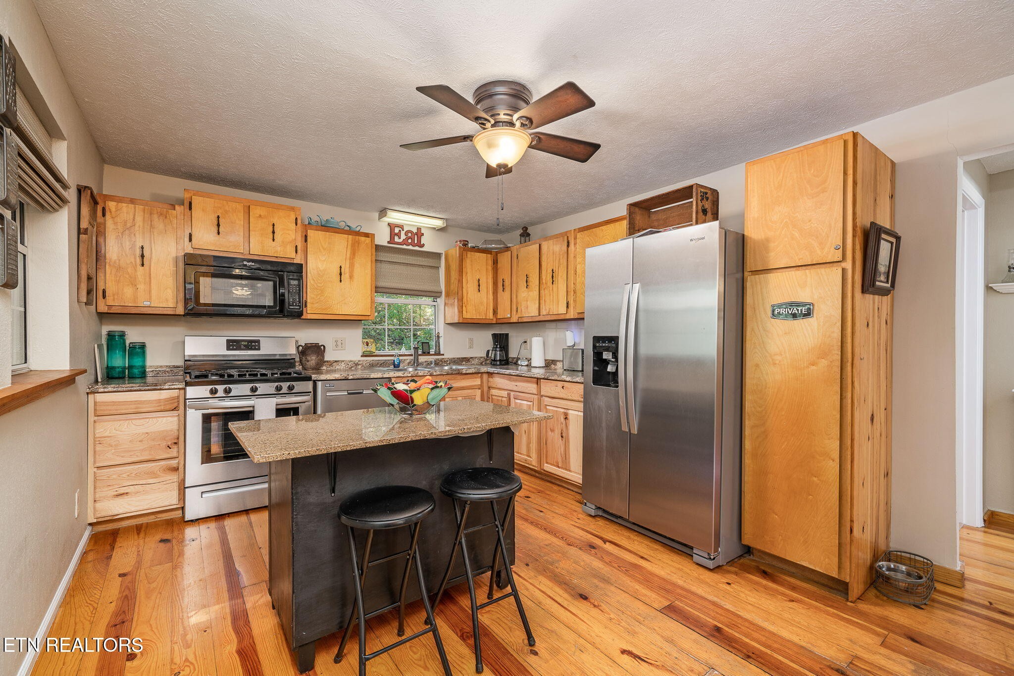 279 Siever Road Crossville, TN 38572 - Photo 5 of 35 a kitchen with stainless steel appliances a refrigerator a stove a sink dishwasher and a dining table with wooden floor