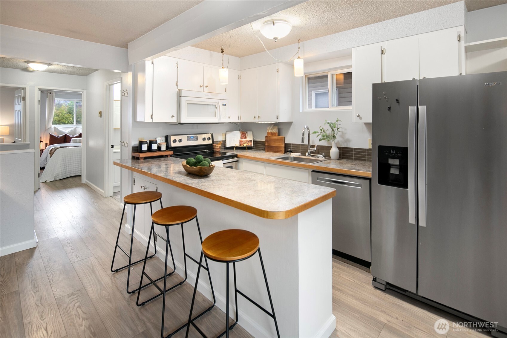 942 North 82nd Street Seattle, WA 98103 - Photo 4 of 16 a kitchen with stainless steel appliances granite countertop a stove a refrigerator a sink a dining table and chairs with wooden floor