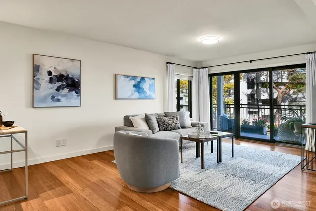 a living room with furniture large window and wooden floor