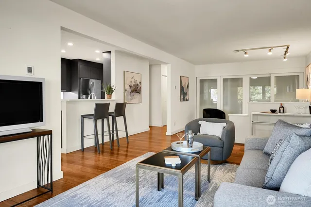 a living room with furniture a flat screen tv and kitchen view