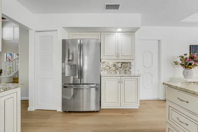 a kitchen with stainless steel appliances granite countertop a refrigerator a stove and white cabinets with wooden floor