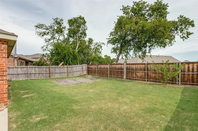a view of a yard with plants and wooden fence