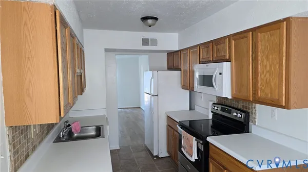 a kitchen with granite countertop a refrigerator a stove and a sink