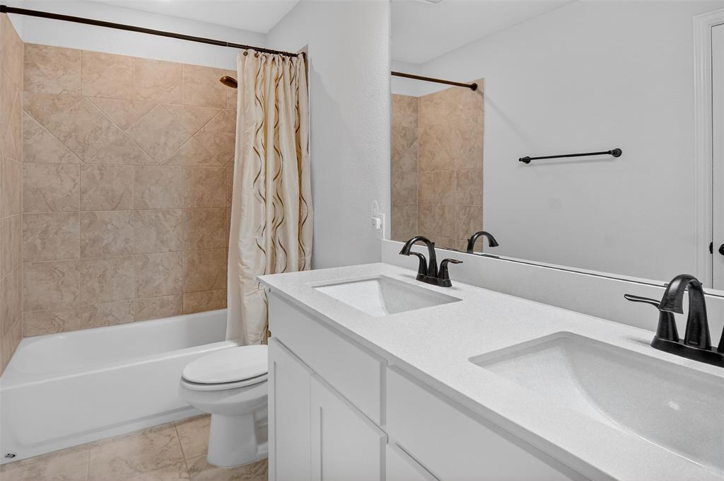 157 Misty Mountain Lane Rhome, TX 76078 - Photo 29 of 40 Second floor bathroom featuring double vanity and shower / bath combination with curtain