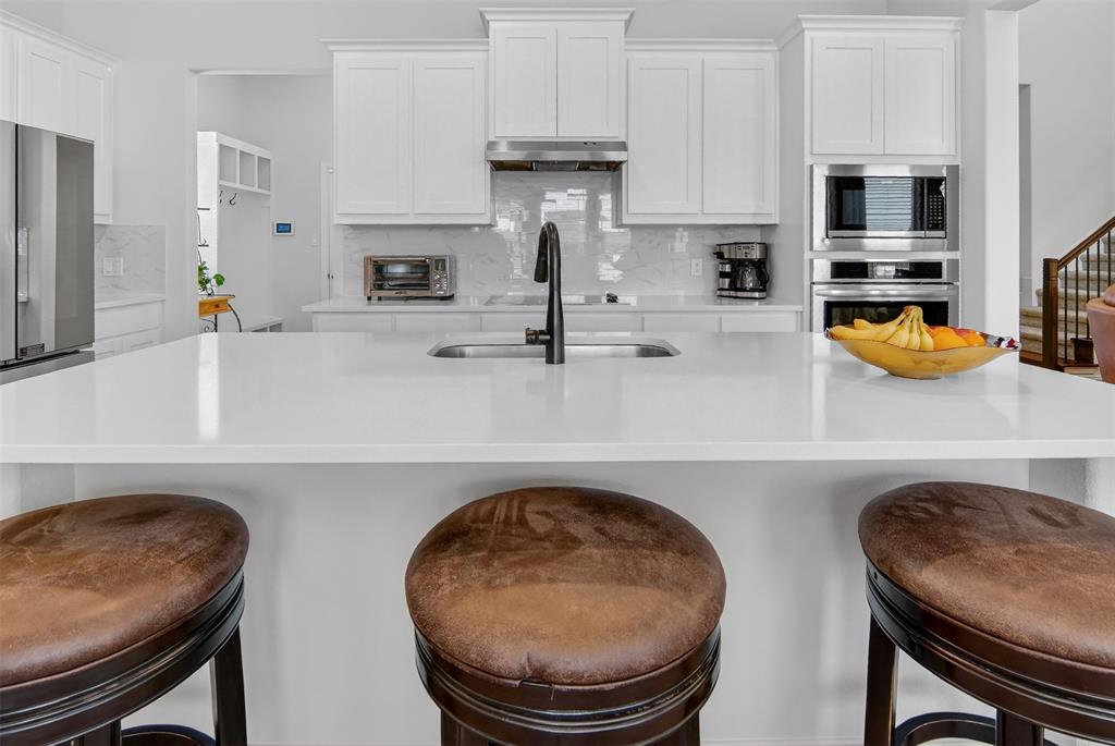 157 Misty Mountain Lane Rhome, TX 76078 - Photo 10 of 40 Kitchen with a kitchen breakfast bar, stainless steel appliances, a large island, and white cabinetry