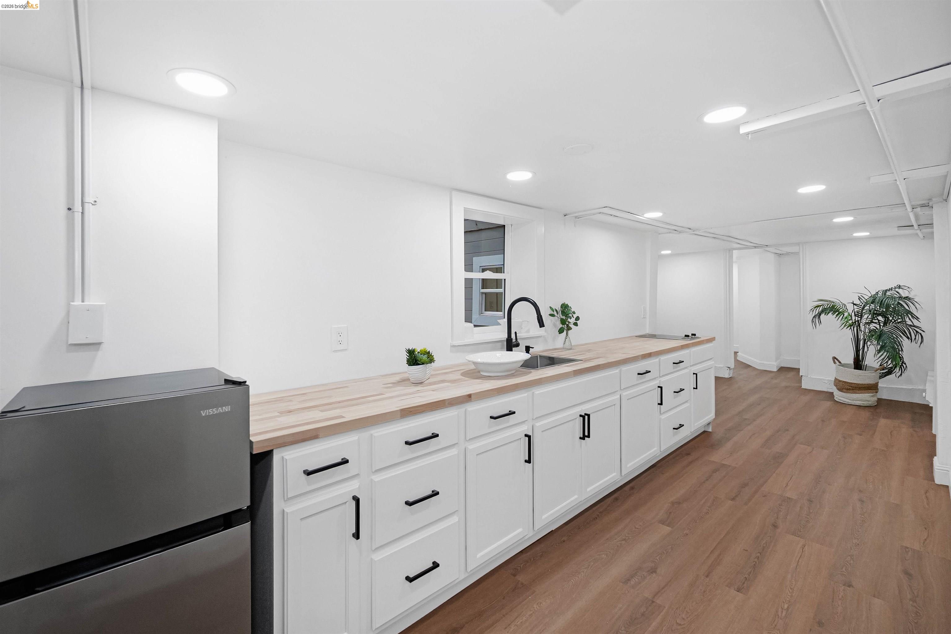 1812 Woolsey Street Berkeley, CA 94703 - Photo 37 of 48 Extended kitchen area featuring wood-finish countertops, white cabinetry with matte black hardware, and a single basin sink with a black gooseneck faucet