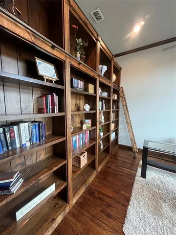 a view of an empty room with wooden floor and book shelf