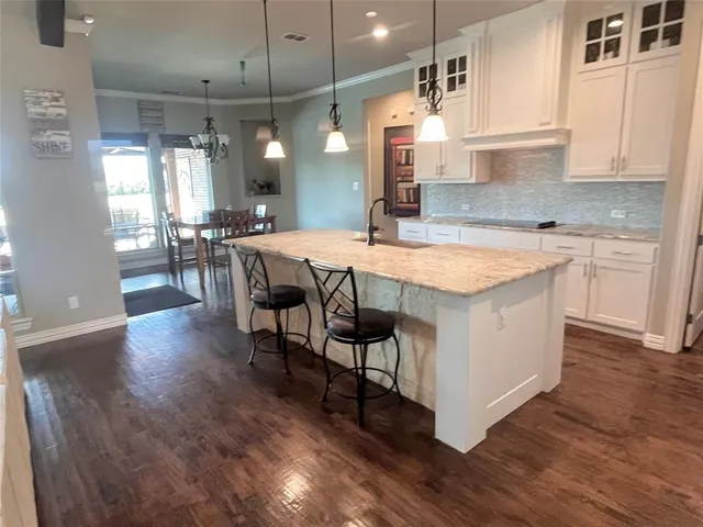 a kitchen with stainless steel appliances granite countertop a table chairs sink and cabinets